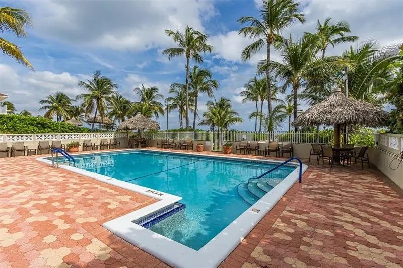 The pool at Christopher House under the palms, with a tiki hut beside it.